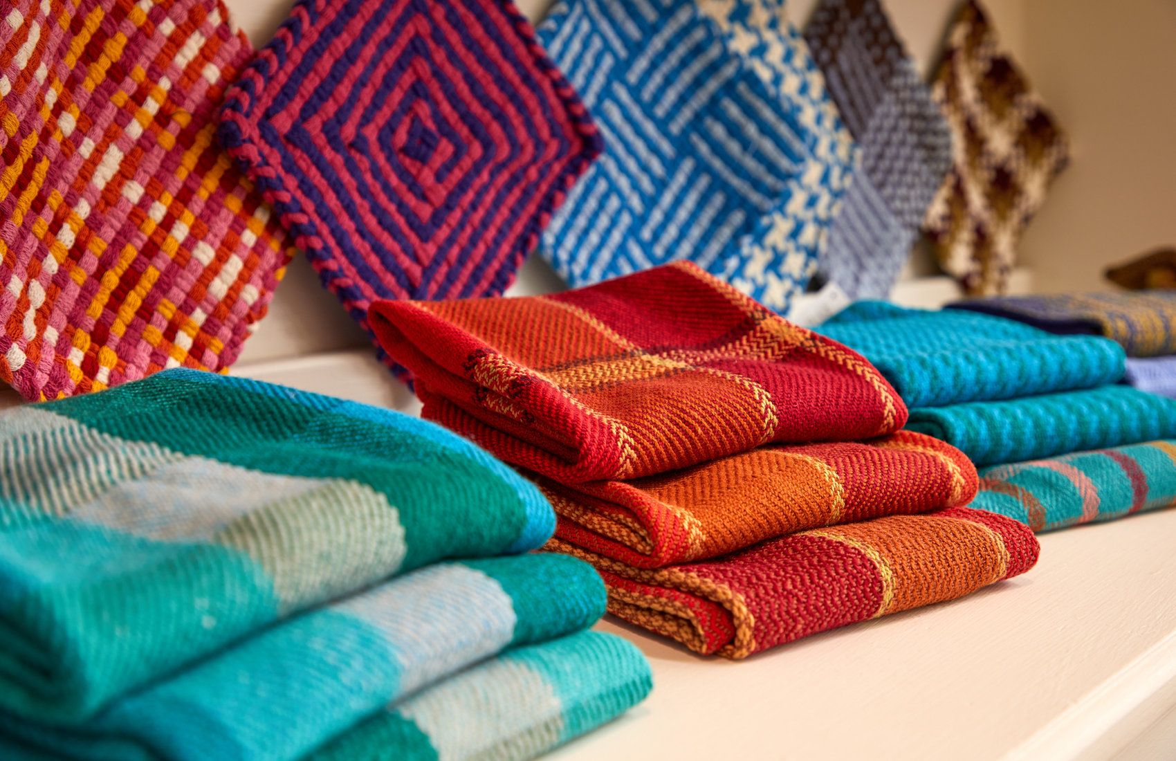 Handwoven blankets and runners stacked in the studio